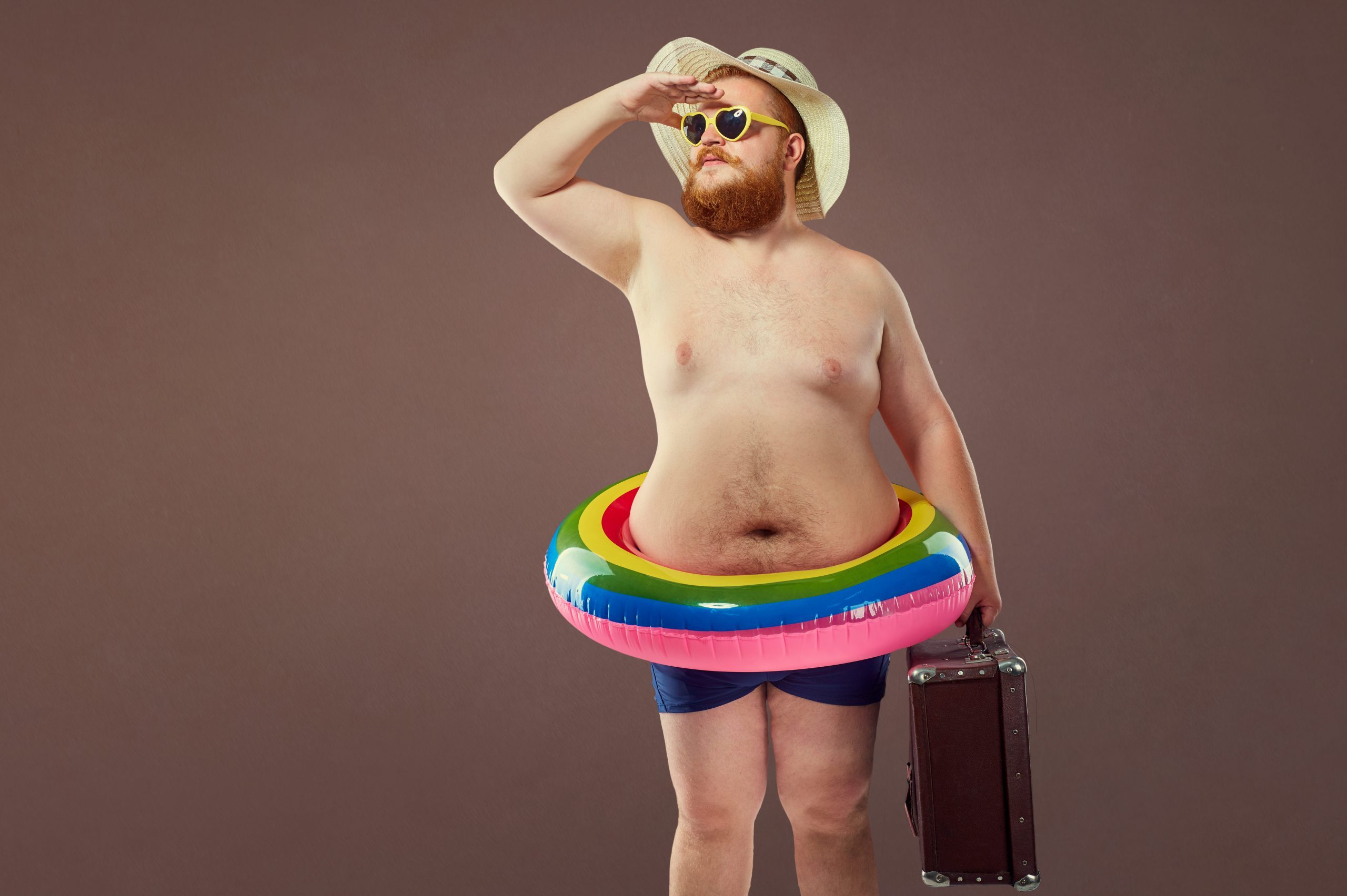 Funny fat bearded man with a suitcase in a hat and glasses on va