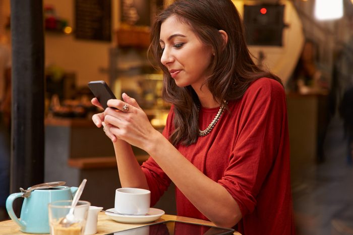 Woman Viewed Through Window Of Caf�¢?? Using Mobile Phone