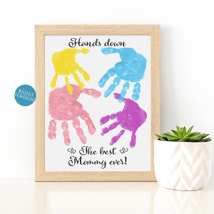 Colorful handprints arranged on a framed print, saying 