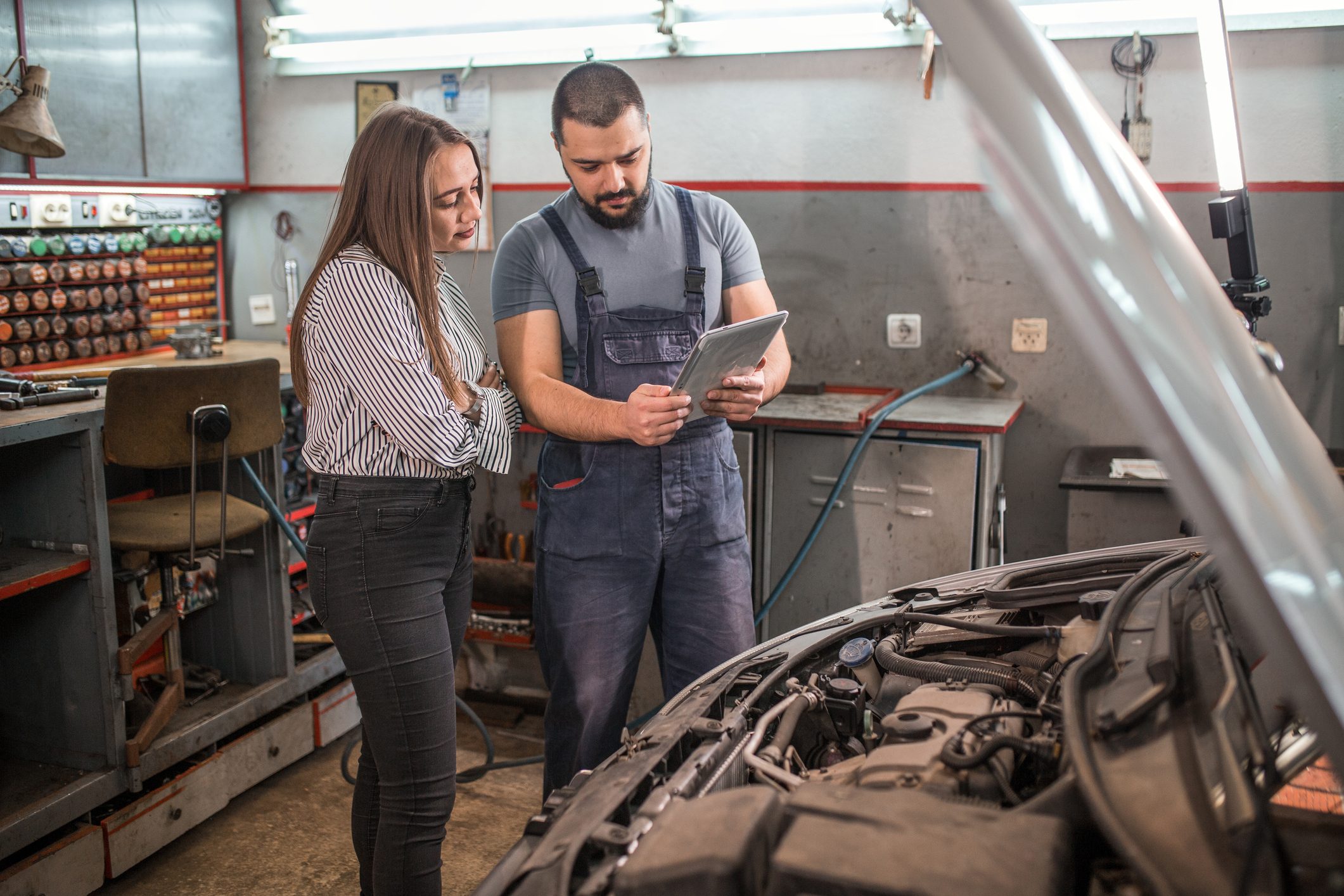 Car mechanic with tablet showing the problems to woman customer in auto repair shop