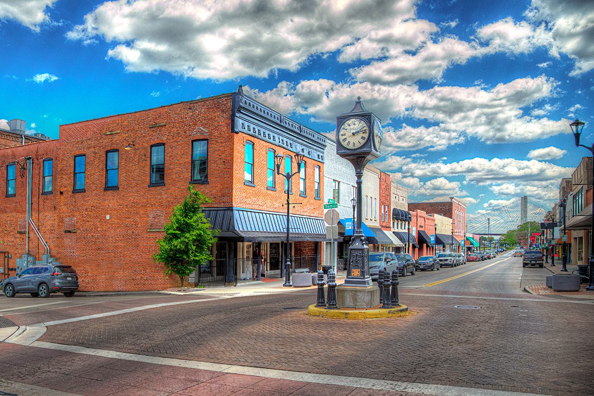Cape Girardeau Missouri own clock in the center, An old painted coco cola sign on the side of a red brick building. Sky full of a flock of floating clouds